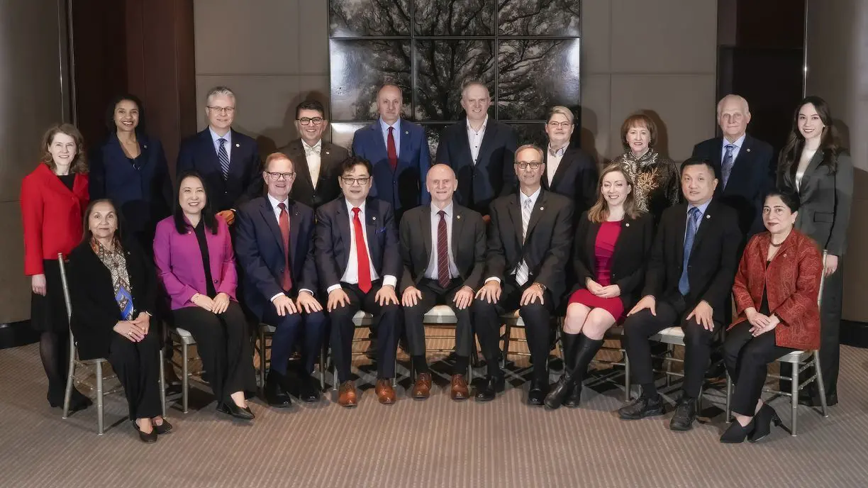 A group of professionals sit and stand in two rows and smile for the camera.